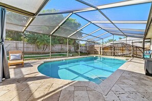 Ein überdachter Außenpool mit freiem Blick auf die Umgebung, darunter eine Holzterrasse und ein umzäunter Garten.