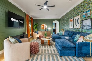 A living room with a sofa, armchair, and a TV on the wall.