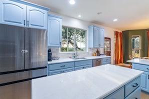 Una cocina moderna con electrodomésticos de acero inoxidable, armarios azul claro y una encimera de mármol.