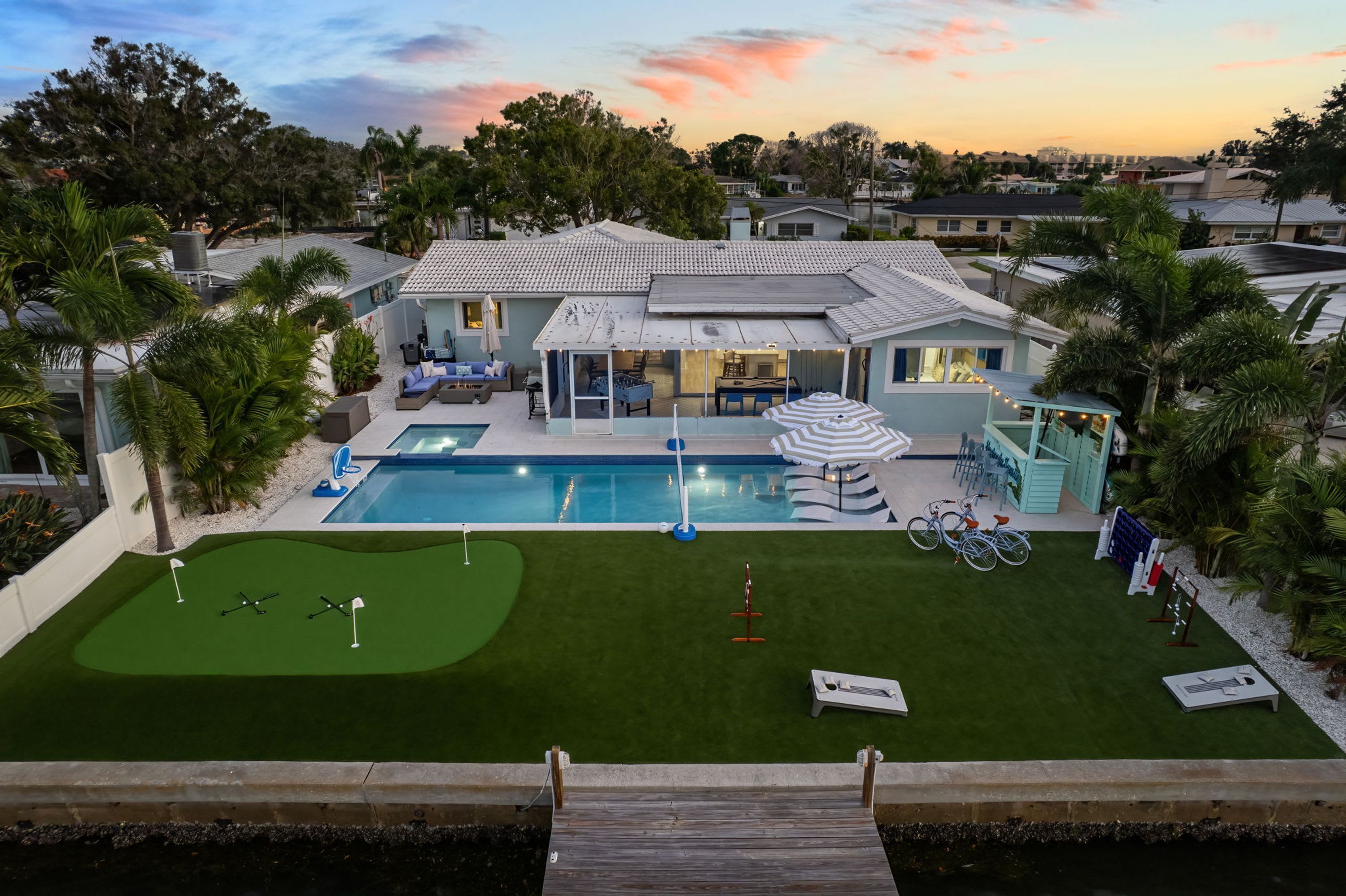 A residential property with a swimming pool, a patio area, and a small putting green.