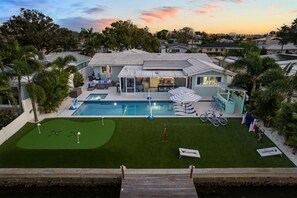 A residential property with a swimming pool, a patio area, and a small putting green. - Waterfront Walk to Beach Pool Kayaks Bikes (Indian Rocks Beach)