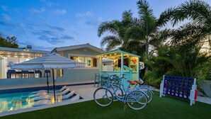 A pool area with a small kiosk, bicycles, and a fence with a game. - Waterfront Walk to Beach Pool Kayaks Bikes (Indian Rocks Beach)