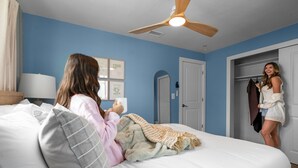 A bedroom with a bed, a ceiling fan, a door, and a wall with framed pictures. - Waterfront Walk to Beach Pool Kayaks Bikes (Indian Rocks Beach)