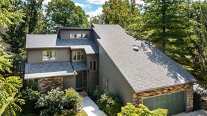 Una casa de dos plantas con fachada de piedra, un garaje y un césped bien cuidado.