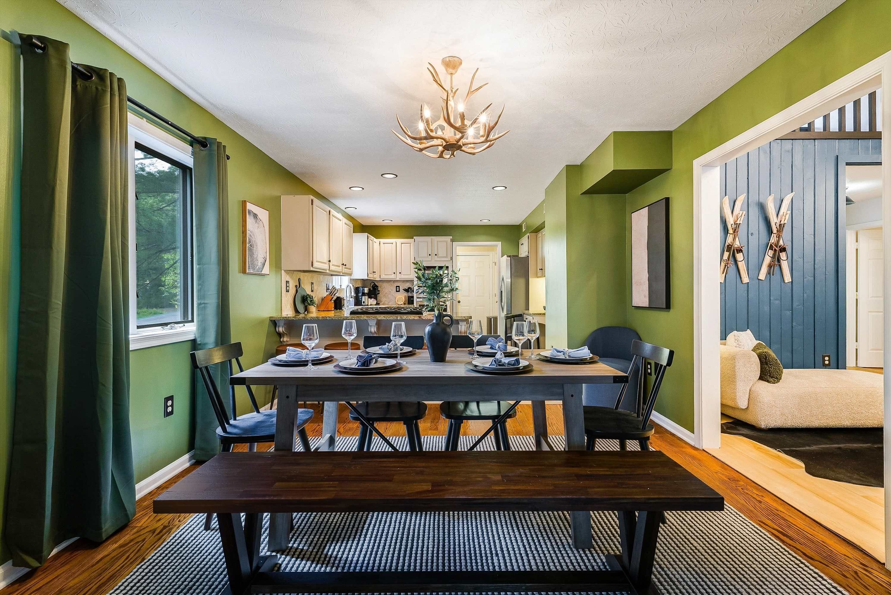 A dining area with a dark wooden table, chairs, and a chandelier.