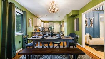 A dining area with a dark wooden table, chairs, and a chandelier.