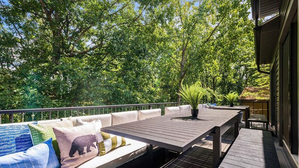 Una terraza al aire libre con un sofá, una mesa y una planta en maceta.