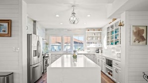 Una cocina moderna con una isla central, electrodomésticos de acero inoxidable y un amplio ventanal que proporciona luz natural.