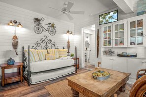 Ein Zimmer mit einer Couch, einem Holztisch, einem Deckenventilator und einem Fernseher.