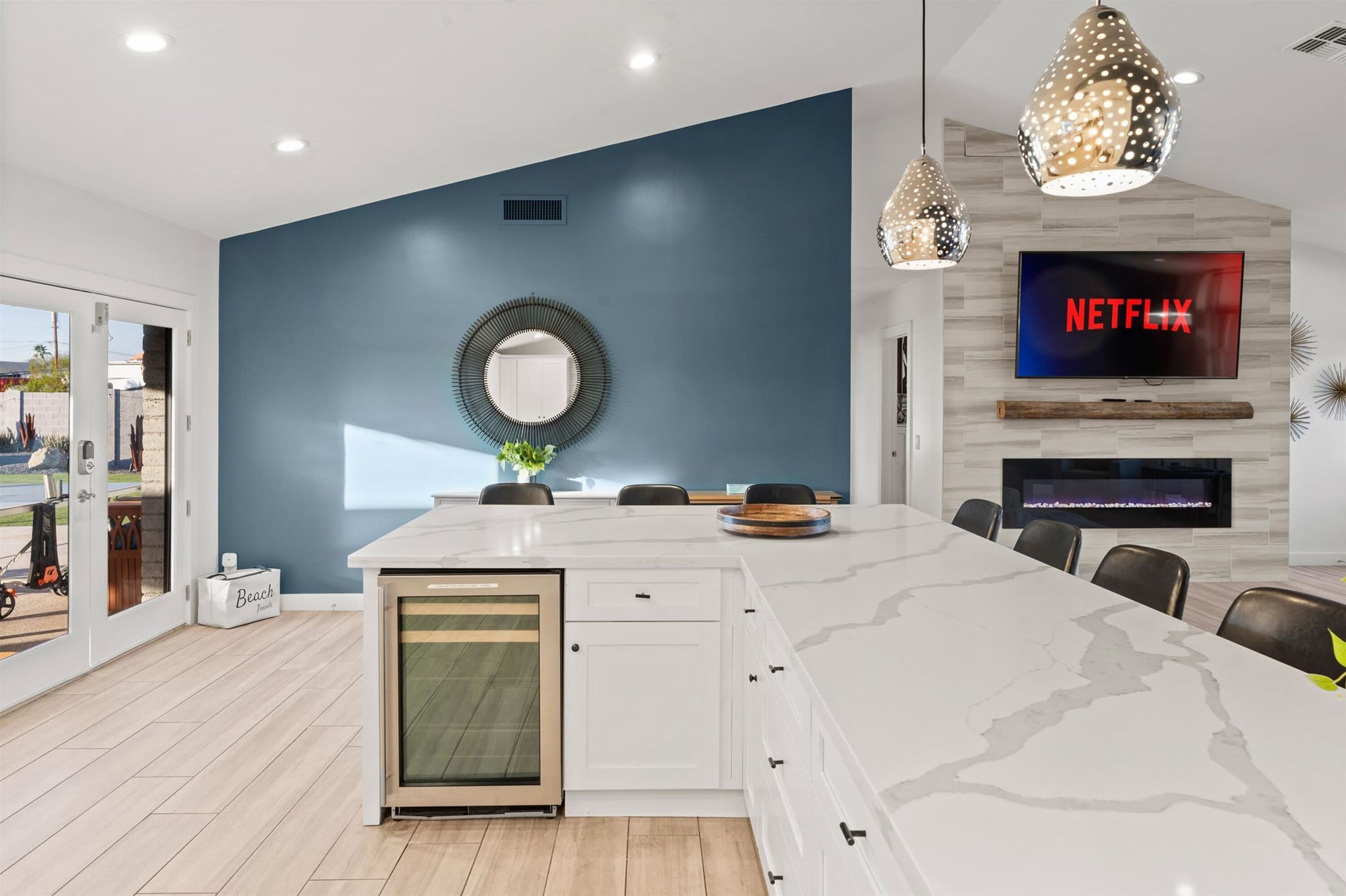 A modern kitchen with a large island, a built-in oven, and a TV mounted on the wall.