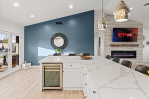 Eine moderne Küche mit einer großen Kochinsel, einem eingebauten Backofen und einem an der Wand befestigten Fernseher.