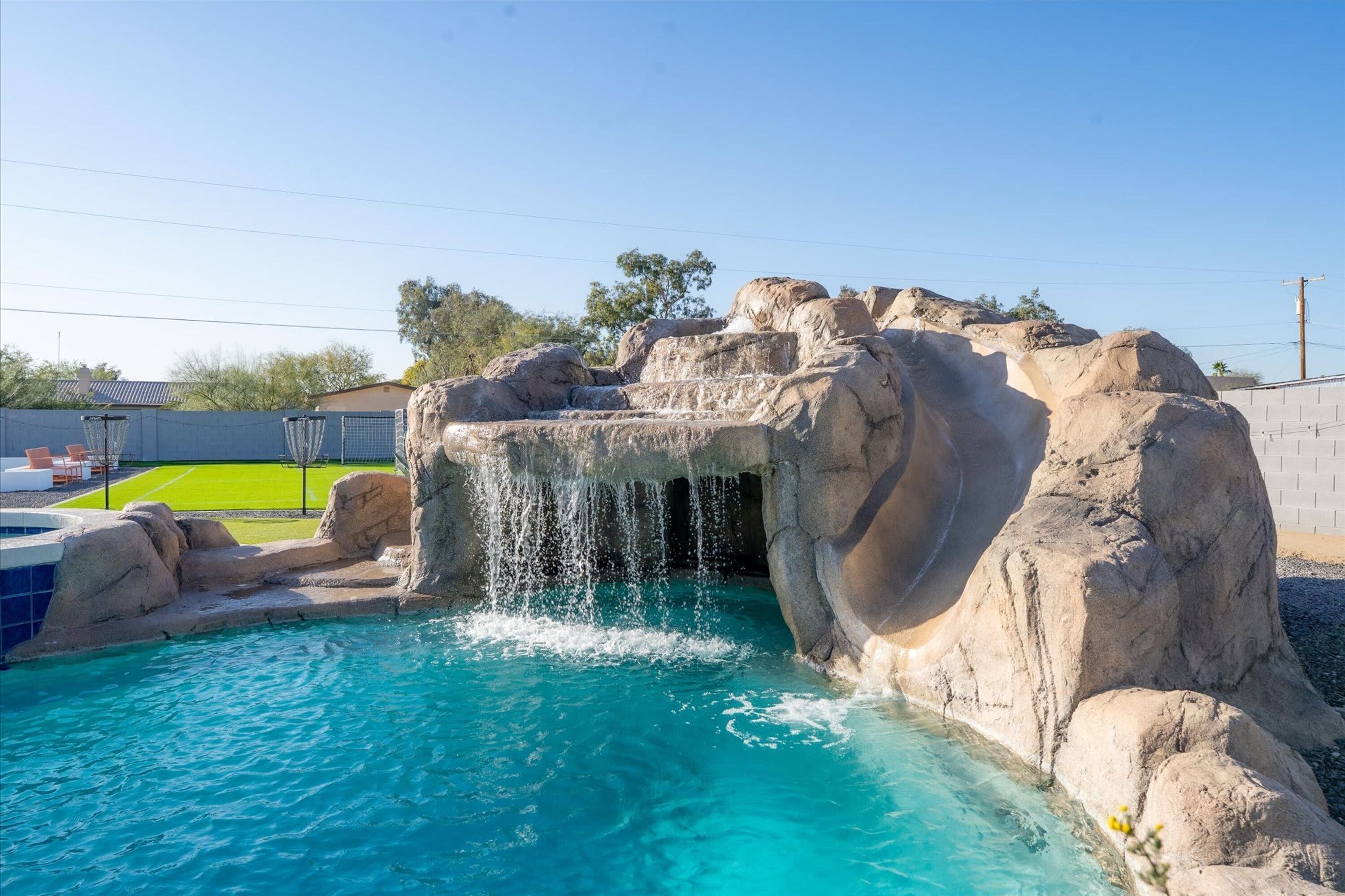 A swimming pool with a waterfall feature surrounded by rocks.