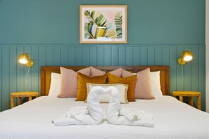 A neatly made bed with white linens, a heart-shaped towel arrangement, and a framed tropical leaf artwork above it. - Poolside Oasis Sleeps 8 Game Room Putt Putt (Bradenton)