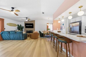 A modern living room with a sofa, a TV, and a ceiling fan. - Poolside Oasis Sleeps 8 Game Room Putt Putt (Bradenton)