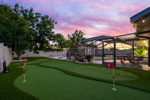 A golf course with a glass enclosure, a number 2 flag, and a sunset sky. - Poolside Oasis Sleeps 8 Game Room Putt Putt (Bradenton)