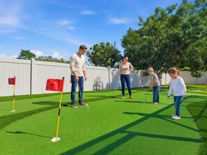 A group of people playing golf on a green field with a white fence in the background. - Poolside Oasis Sleeps 8 Game Room Putt Putt (Bradenton)