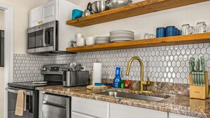 Una cocina moderna con electrodomésticos de acero inoxidable, encimera de granito y salpicadero de azulejos.