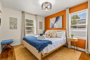 A bedroom with a bed, a side table, a bench, and a ceiling light. - Sunny Citrus Escape Min to Midtown Dog-friendly (Tampa)