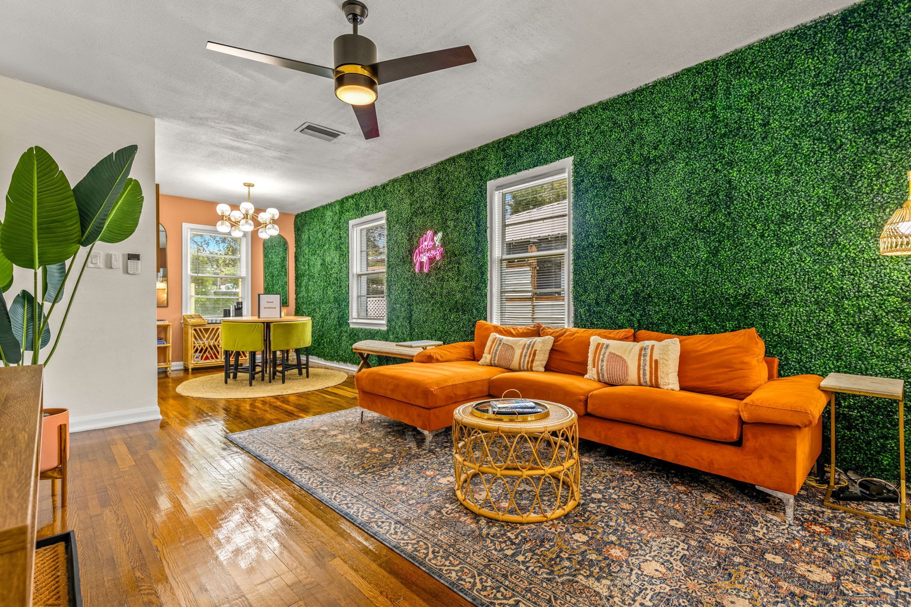 A living room with a green wall, orange sofa, and a ceiling fan.