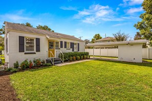 A single-story house with a front yard, a small porch, and a visible door. - Sunny Citrus Escape Min to Midtown Dog-friendly (Tampa)