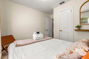 Ein Schlafzimmer mit einem Bett, einem Sessel, einer Tür und einer kleinen Pflanze.
