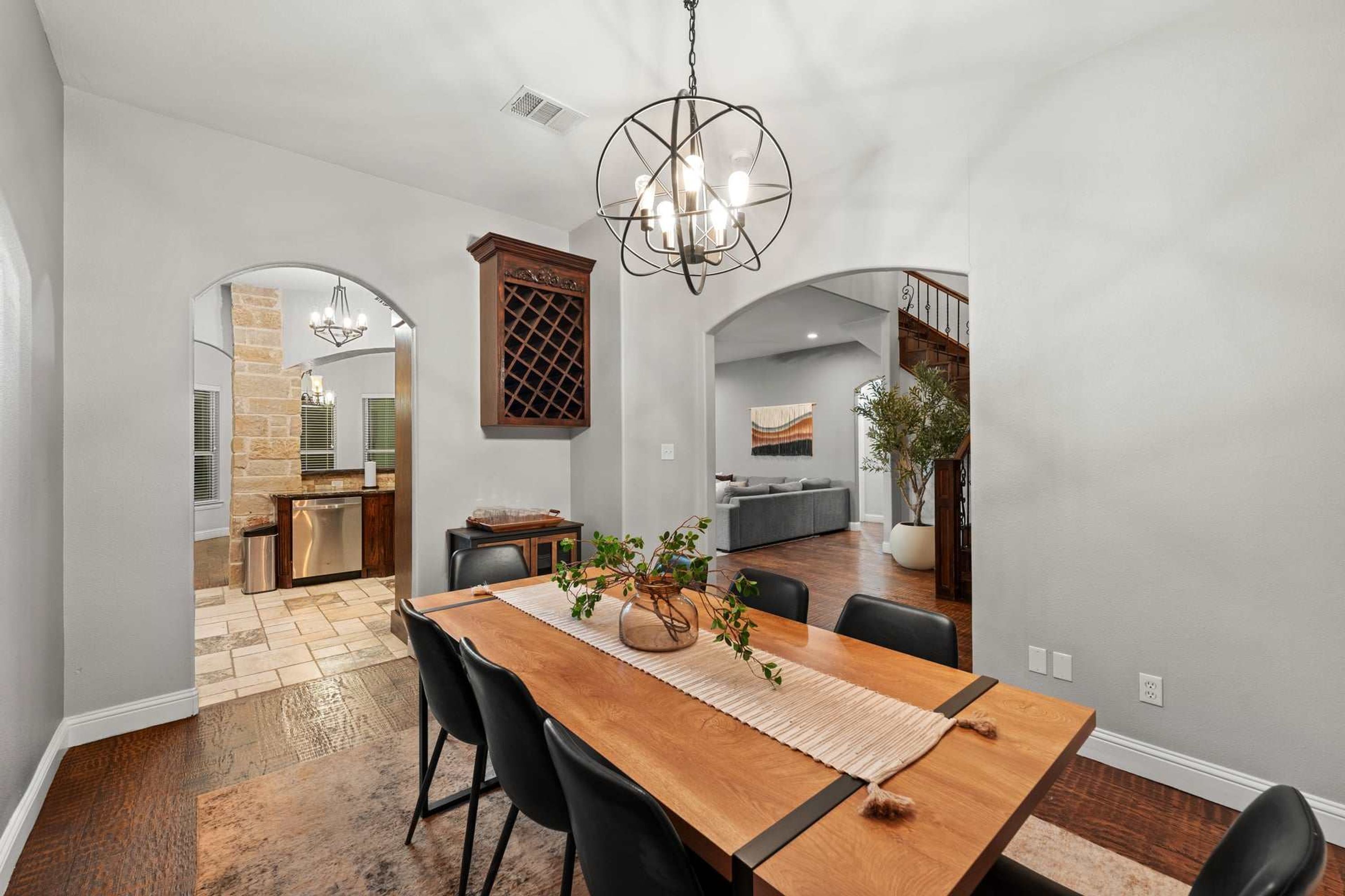 A spacious dining area with a wooden table, black chairs, and a hanging light fixture.