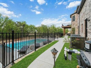 A backyard with a swimming pool, a barbecue grill, and a stone building. - The Cove Heated Pool Hot Tub Lake Access (Denton)