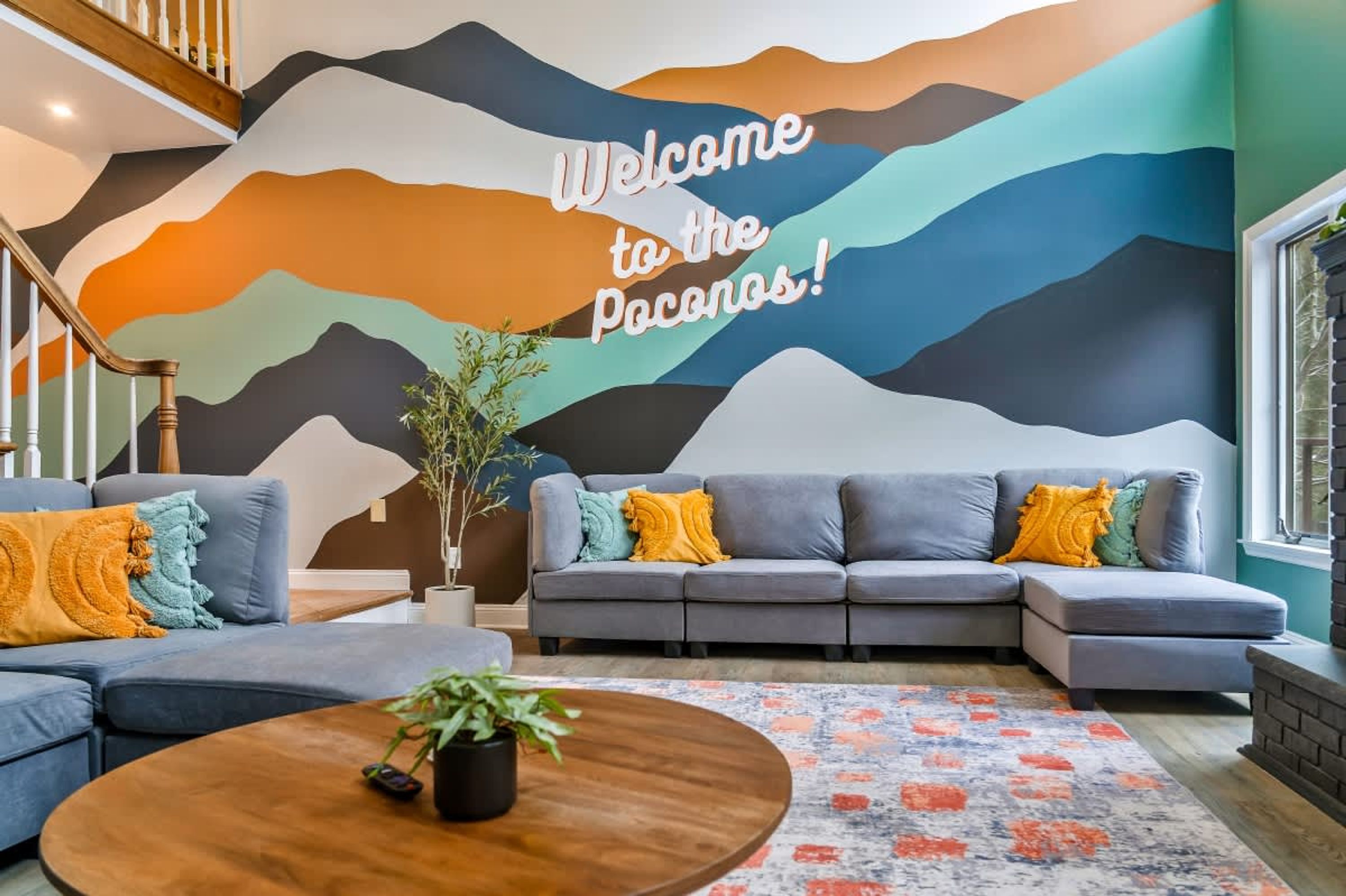 A modern living room with a large wall mural, a grey sofa set, and a wooden coffee table.