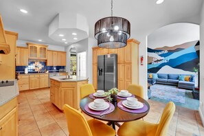 Une cuisine moderne avec des meubles en bois, un îlot central et un coin repas avec des chaises jaunes et une table dressée pour quatre personnes.