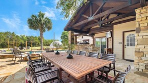 An outdoor patio with a wooden table and chairs, a stone wall, and a pool. - Birdie Creek Ranch - Private Golf Course Resort (Driftwood)