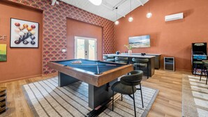A pool table in a room with patterned wallpaper, a bar area, and a television. - Birdie Creek Ranch - Private Golf Course Resort (Driftwood)