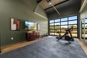 A gym with exercise equipment, large windows, and artwork on the walls. - Birdie Creek Ranch - Private Golf Course Resort (Driftwood)
