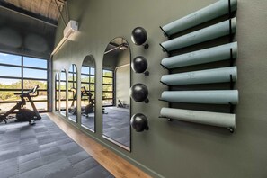 Un gimnasio con equipo de ejercicio, espejos y un perchero para toallas en la pared.