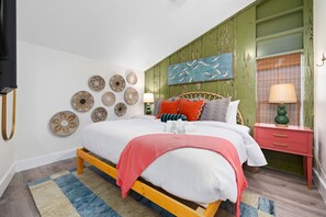 Ein Schlafzimmer mit einem Bett, Nachttischen, einer Wand mit dekorativen Tellern und einem Gemälde.