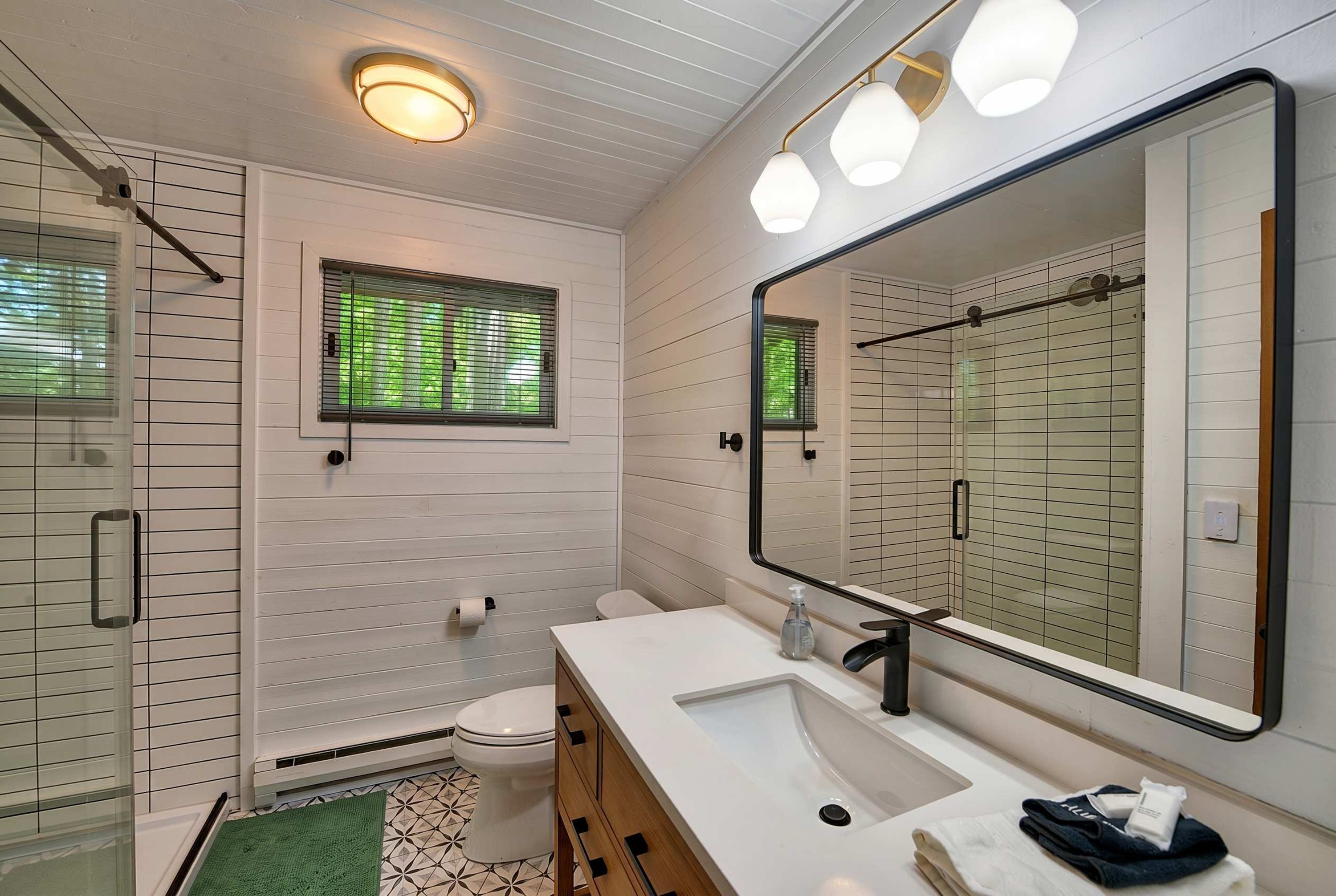Une salle de bain avec un meuble-lavabo blanc, un grand miroir, des toilettes et un espace douche.