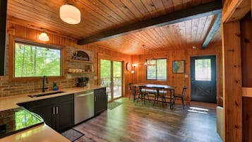 Interior de madera con cocina, comedor y una puerta que da al exterior.