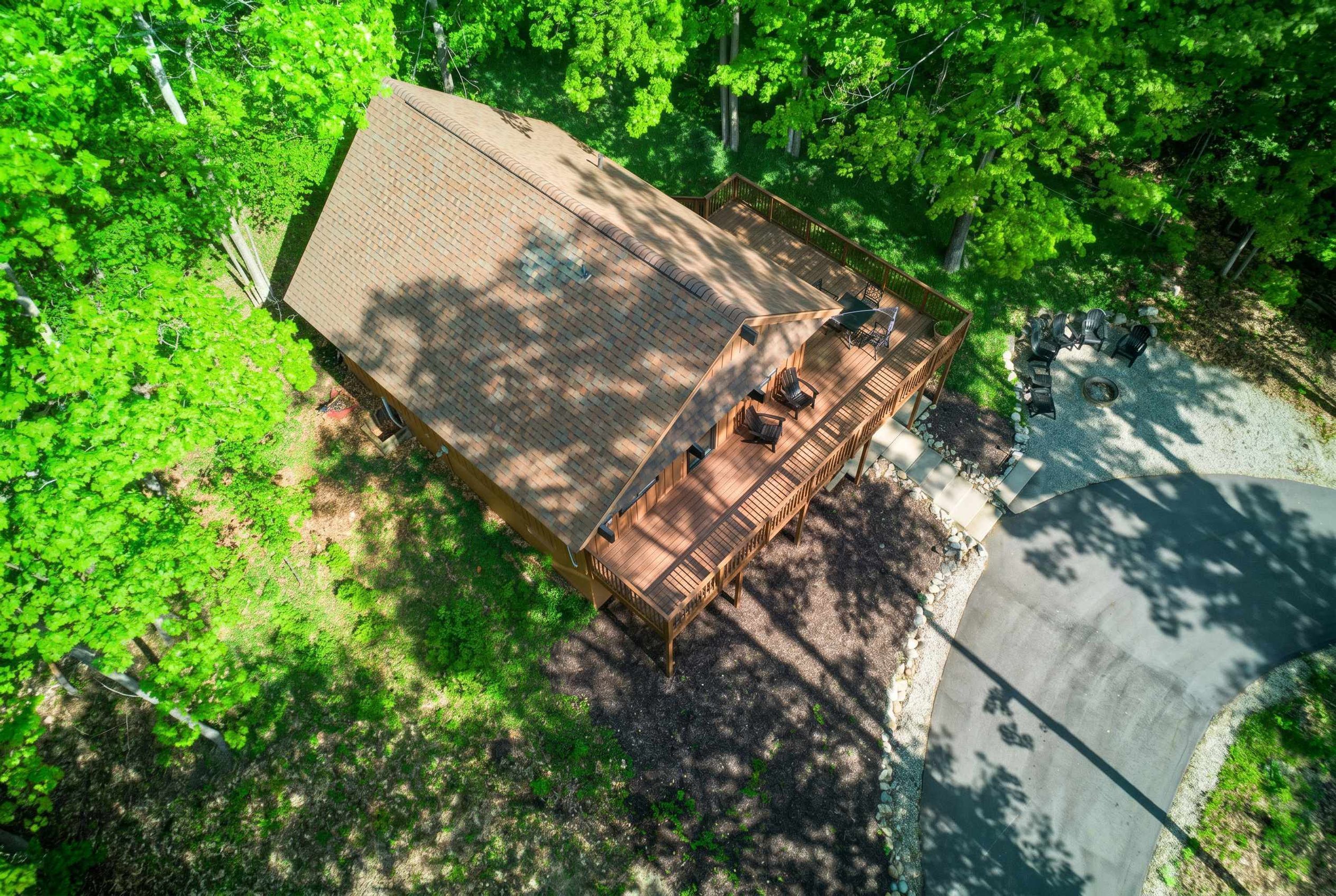 Vue aérienne d’un chalet doté d’une terrasse, entouré d’une forêt dense.