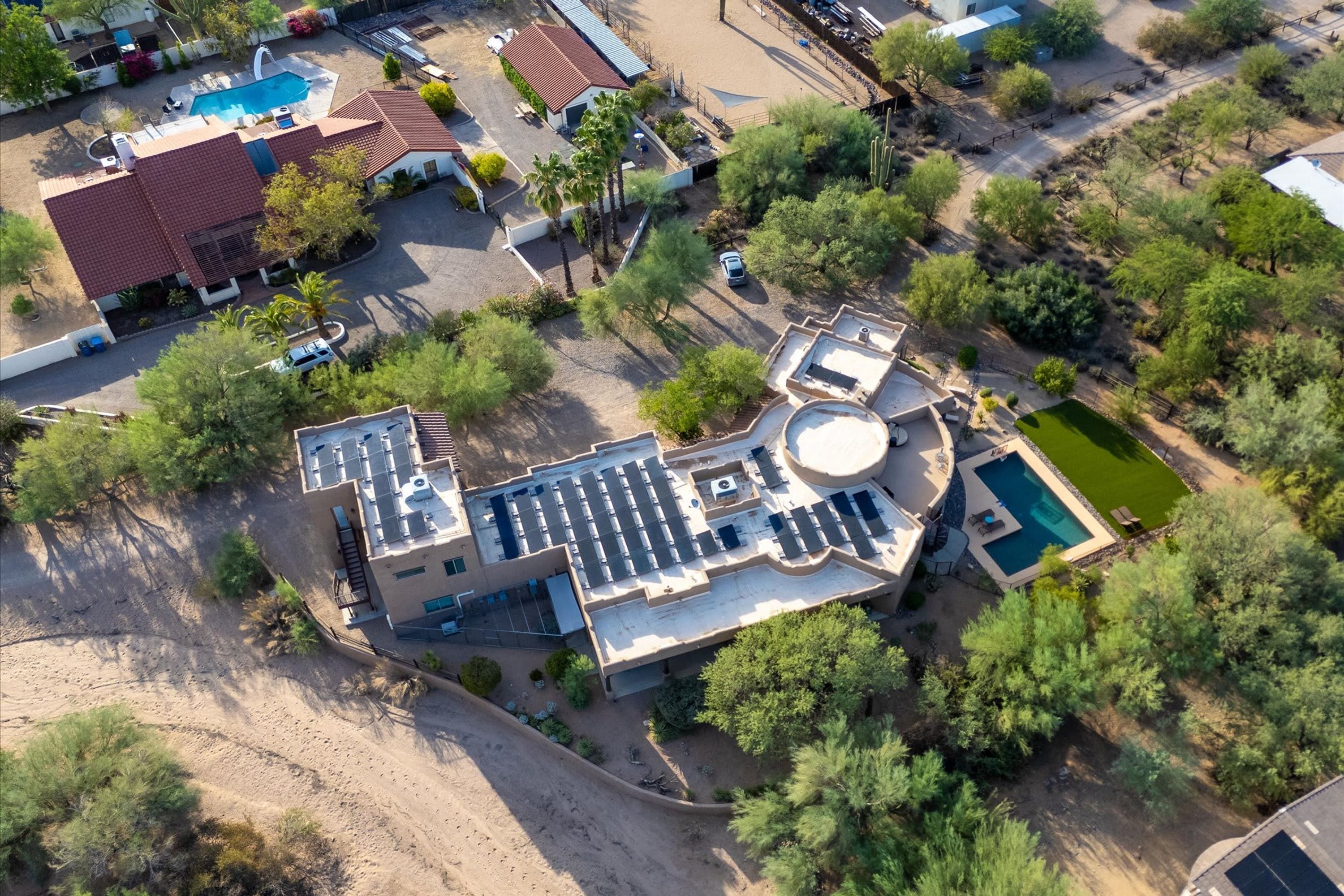 An aerial view of a residential property with a swimming pool, a covered patio, and a landscaped garden.
