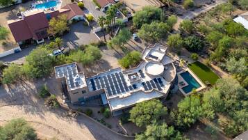 An aerial view of a residential property with a swimming pool, a covered patio, and a landscaped garden.