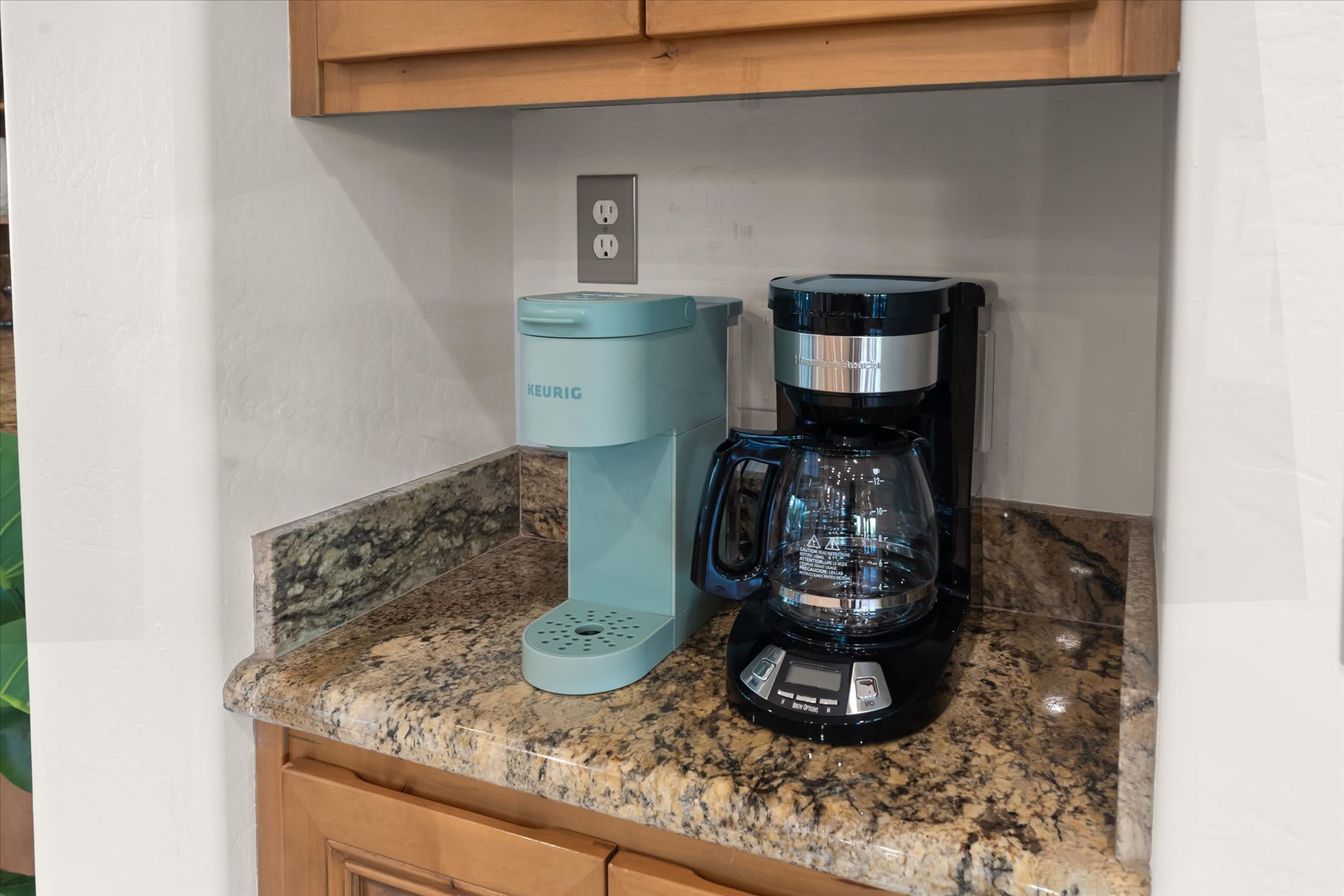 A kitchen counter with a Keurig coffee maker and a black coffee maker.