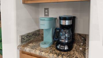 A kitchen counter with a Keurig coffee maker and a black coffee maker.