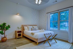 A bedroom with a bed, bedside table, lamp, potted plant, and a window with a view of the outside. - TOP Memphis BnB The Soul House Near Beale St (Memphis)