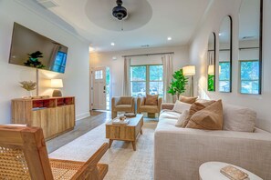 A modern living room with a sofa, armchairs, a coffee table, and a TV mounted on the wall. - TOP Memphis BnB The Soul House Near Beale St (Memphis)