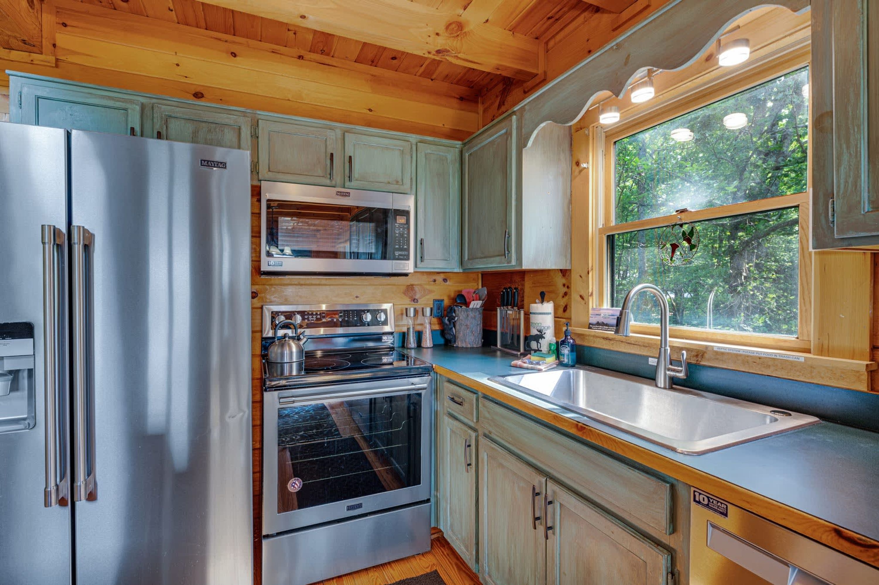 A compact kitchen with a refrigerator, microwave, oven, and sink.