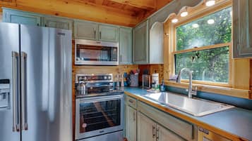 A compact kitchen with a refrigerator, microwave, oven, and sink.