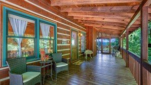 A covered porch with wooden flooring, wicker furniture, and large windows with curtains. - Mountain Views w Slide Hot Tub Game Room (Mineral Bluff)