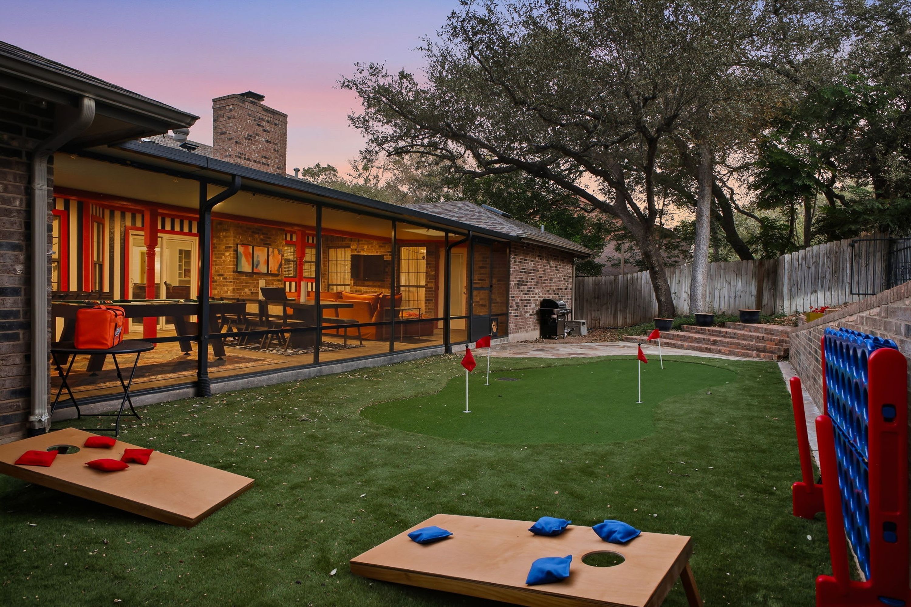 A backyard with a patio, a wooden table, and a grassy area with two small flags.