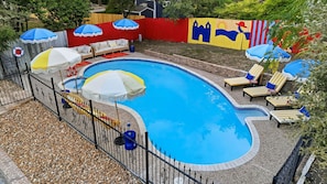 A swimming pool with a curved edge, surrounded by a fence, and equipped with multiple umbrellas. - Sleeps 16 Heated Pool Hot Tub Sport Court (San Antonio)