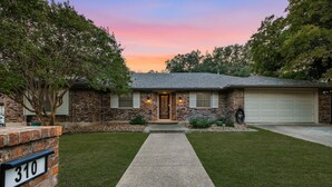 A two-story brick house with a front porch, a driveway, and a well-maintained lawn. - Sleeps 16 Heated Pool Hot Tub Sport Court (San Antonio)