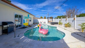A backyard with a swimming pool, a barbecue grill, and a flamingo float. - Backyard Oasis Pool Hot Tub Putt Putt Bar (Largo)